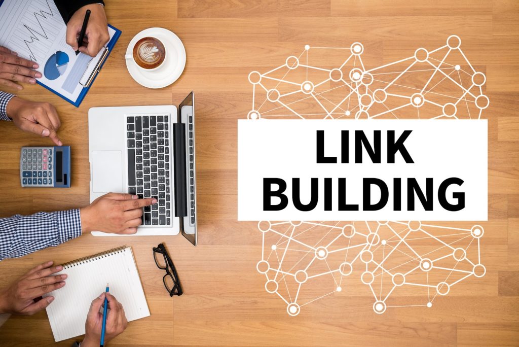 LINK BUILDING Business team hands at work with financial reports and a laptop